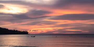 Beautiful sunset over the sea in Phuket, Thailand with colorful clouds and calm water.