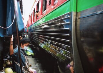 Experience the bustling Maeklong Railway Market in Bangkok with a train passing by closely.