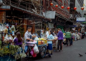 Vibrant street market scene in Asia with diverse vendors selling fresh produce.