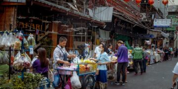 Vibrant street market scene in Asia with diverse vendors selling fresh produce.