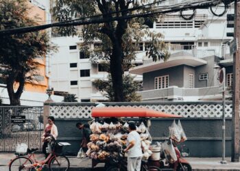 Street vendor with a cart selling goods on a city street in Bangkok, Thailand, showcasing local urban life.
