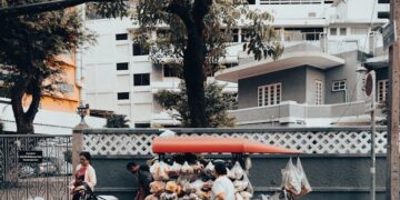 Street vendor with a cart selling goods on a city street in Bangkok, Thailand, showcasing local urban life.